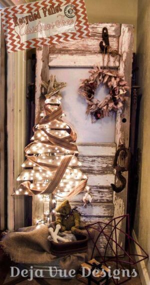 Albero di Natale realizzato con listelli di pedana in legno decorata con lucine e vecchia striscia di tessuto con stella in legno e ghirlanda di foglie di mais e paglia