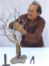 Uomo anziano con occhiali modella la scultura di un albero