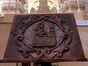 Foto a colori del leggio in legno con l'immagine della guglia della Chiesa S. Maria