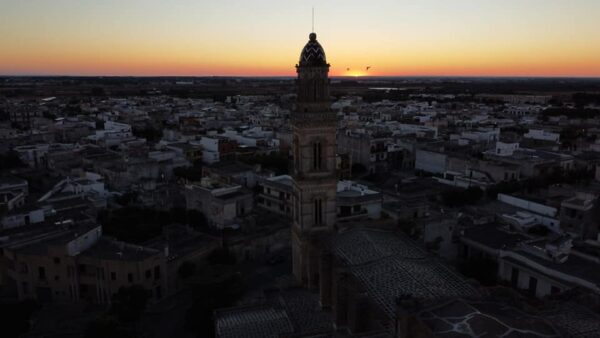 Fotografia dall'alto di centro abitato con chiesa e campanile al tramonto