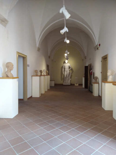 Gallerie con scultura di uomo al centro e teste scolpite sulle pareti ai lati