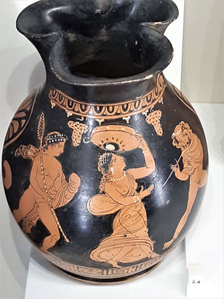 Vaso con fondo nero. figura di donna che suona il tamburello affiancata da due figure maschili